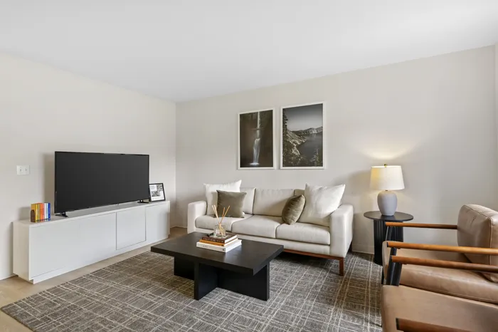 Modern living room with stylish decor, featuring a cozy beige sofa, elegant wooden coffee table, and framed art on the wall.