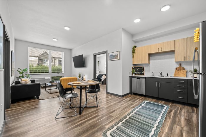 Modern open-concept living space with sleek kitchen, cozy dining area, and bright living room featuring stylish decor and natural light.
