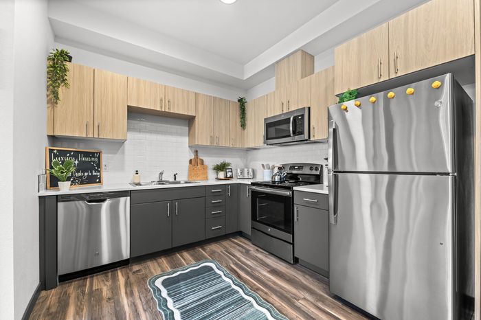 Modern kitchen with sleek stainless steel appliances, stylish two-tone cabinetry, and elegant hardwood flooring.