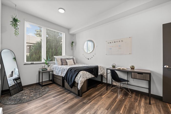 Bright and modern bedroom featuring a cozy bed, stylish desk, and large window with a garden view.