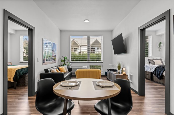 Chic apartment interior showcasing a cozy living area with modern furniture, dining table set for two, and two bright, welcoming bedrooms.