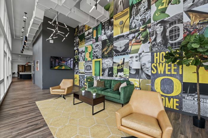 Contemporary lobby with vibrant mural, plush seating, and modern lighting in a chic apartment complex.