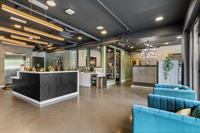 Modern lobby area featuring stylish geometric front desk, vibrant blue seating, and contemporary lighting fixtures, perfect for a welcoming atmosphere.