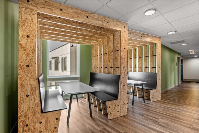 Modern seating area with sleek wooden alcoves and stylish tables, complemented by abundant natural light and a contemporary design.