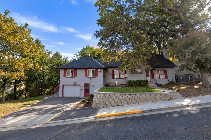 Coug Housing suburban home with red shutters, nestled among mature trees and featuring a spacious front yard.