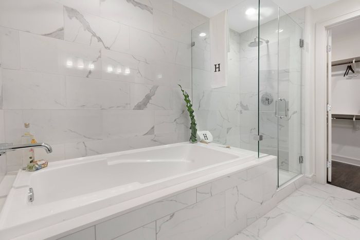 Master bathroom with floor-to-ceiling marble tile, a glass walk-in shower, a full-size soaking tub, and a walk-in closet.