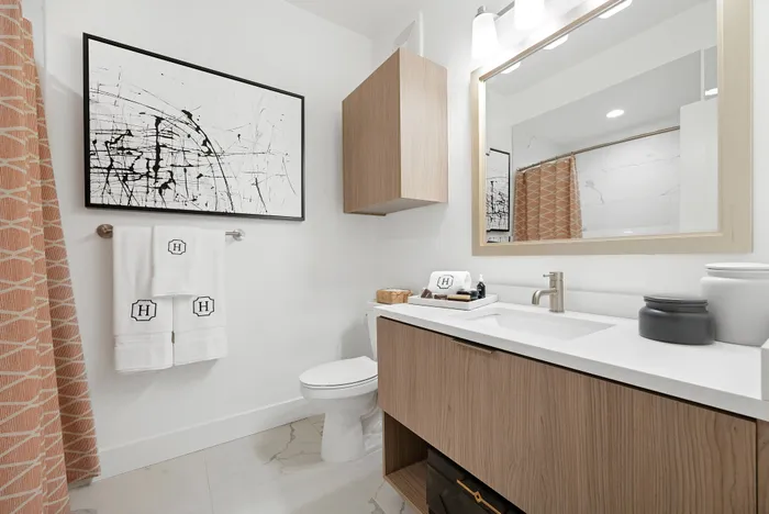 Bathroom with maple cabinets and a white marble countertop.