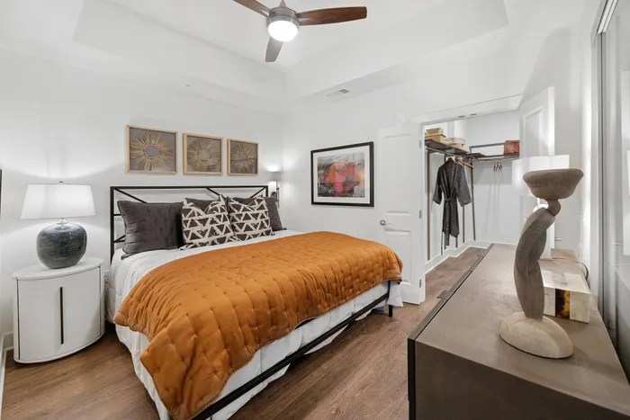 Bedroom with a king-sized bed, recessed ceiling with a fan, and a walk-in closet.