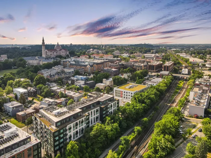 Aerial shot of the Brookland neighborhood, with the Basilica of the National Shrine in the distance and Hanover 8th Street overlooking the tree-lined Red subway line in the foreground.