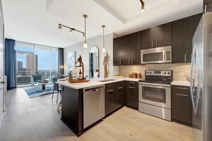 Kitchen with warm wood-style floors, dark wood cabinets, stainless appliances, granite countertops, and a recessed ceiling