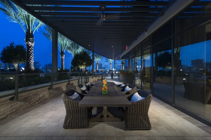 Covered patio adjacent to the pool deck with a 6-person wooden dining table