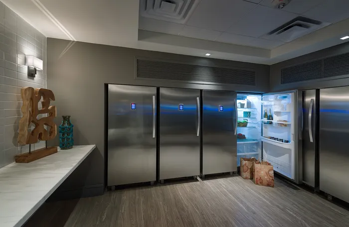 Multiple stainless refrigerators with touchscreen locks along the wall of a room with a marble counter