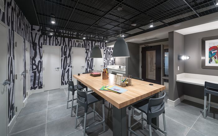 Studio with built-in and freestanding desks, art supplies, 6 closets, a sink, and black-and-white graphical letters printed on the walls
