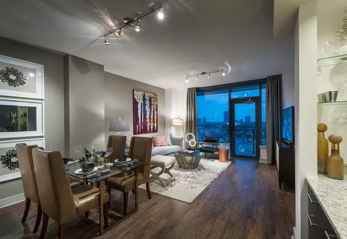 Open-concept living and dining room with high ceilings, full-width floor-to-ceiling windows, wood-style floors, a dry bar, and a taupe accent wall