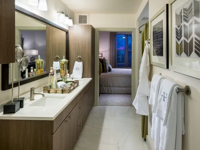Bathroom adjacent to the master bed with a white quartz dual vanity countertop, white marble-style floors, and dark wood cabinetry.