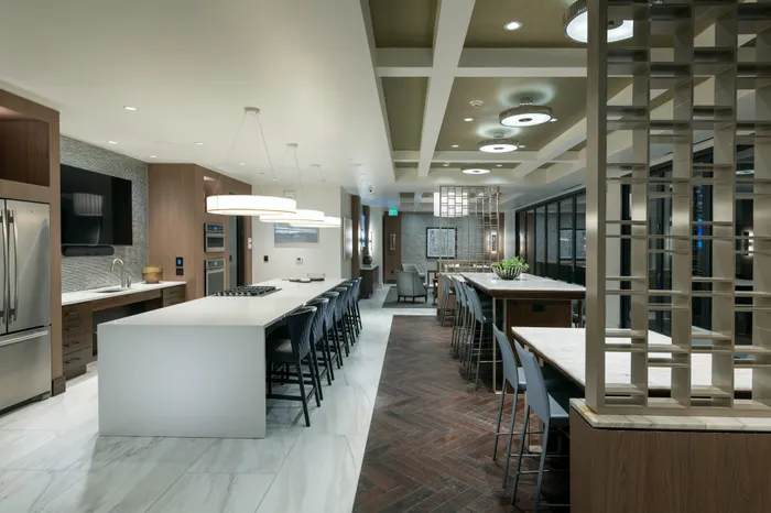 Alternate view of the clubhouse space showing the large HDTV mounted in the catering kitchen and the white marble floors.