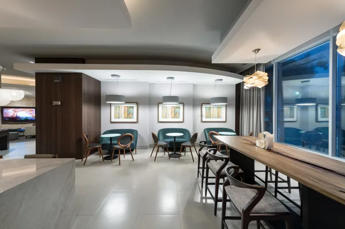 A work area including a wooden table with 6 chairs and cafe-style seating along the wall.