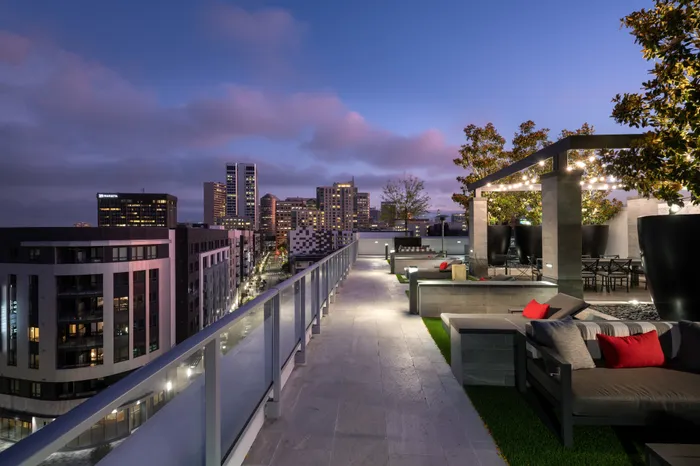 A landscaped rooftop entertaining area with a city skyline view and multiple dining and seating areas.