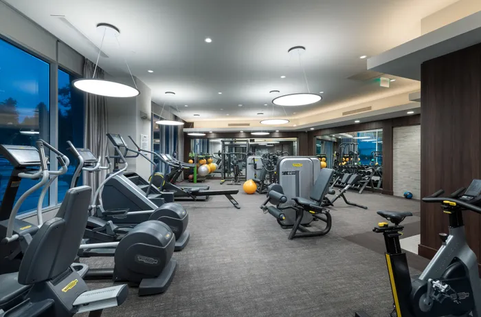 Treadmills, ellipticals, stair climbers, and weight machines in the gym.