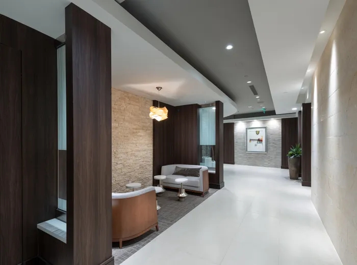 Seating area with two loveseats tucked in a quiet nook. There is wood paneling on the walls and marble tile on the floors.