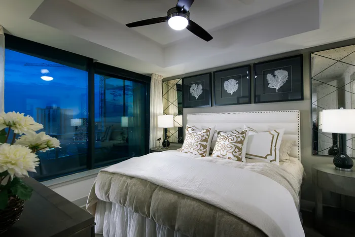 Bedroom featuring a large bed and dresser, recessed ceiling with a fan, full-width window, and white walls with a gray accent wall.