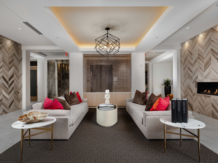 Resident lounge with two white couches, a coffee table, two end tables, chevron wood-style walls and a fireplace on the wall.