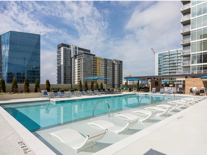 Outdoor pool deck with a lounge chairs and a skyline view.