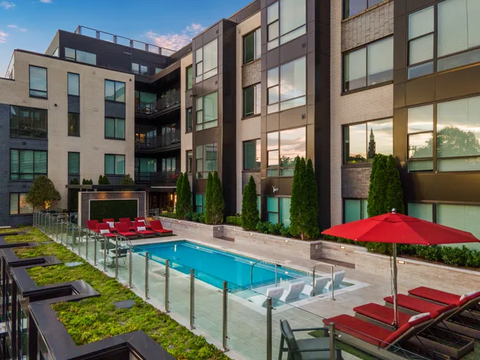 Elevated outdoor pool deck with landscaping and upholstered lounge chairs.