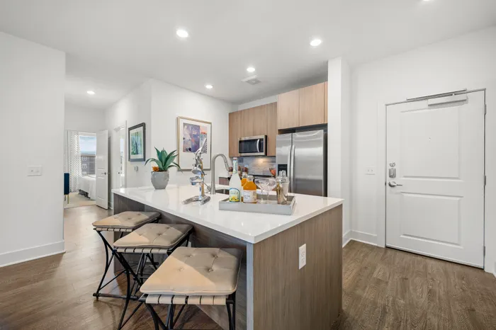 kitchen island with white quartz countertop and 3 counter stools