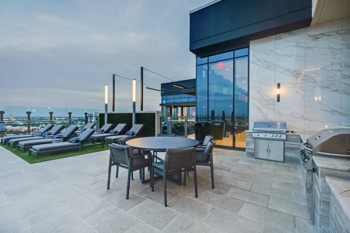 rooftop lounge area with grills dining table and sun loungers