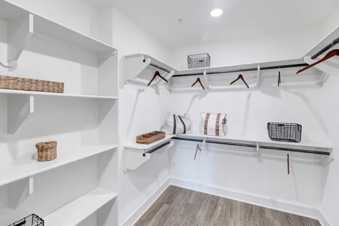 walk-in closet with white wooden shelving and hanging racks
