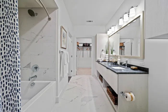 bathroom with two sinks, large mirror, shower tub combo and closet attached