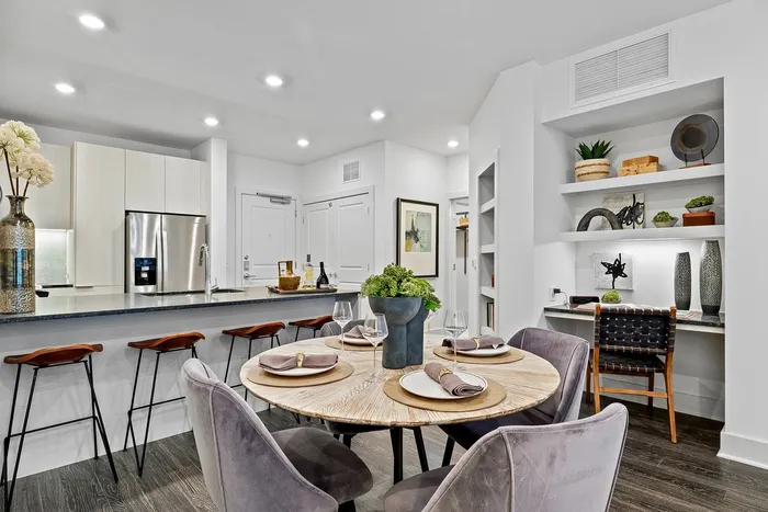 dining table with kitchen counter with stools and bookshelves in background