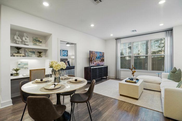 living room and dining room with dining table, four chairs, tv, tv stand and bookshelf with built in desk and decor pieces