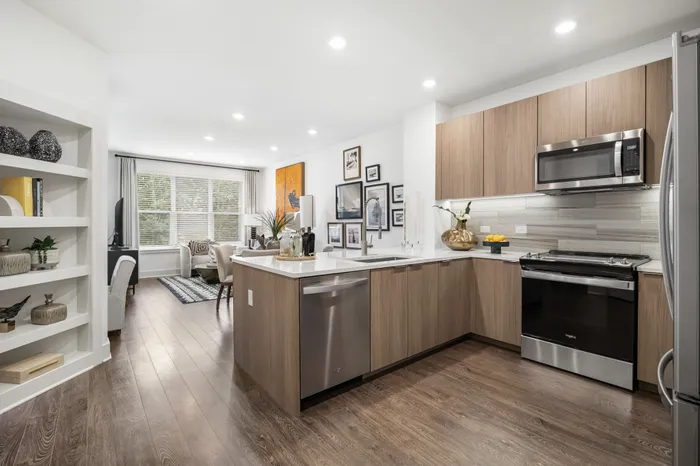 apartment kitchen with brown wood flooring, white counters, brown cabinets and stainless steel appliances