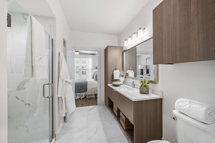 bathroom with white marble tile, white counters, and glass framed shower