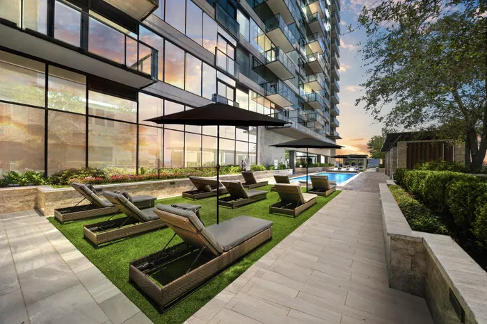 angled view of the cushioned chaise loungers next toa resort style pool of a highrise building