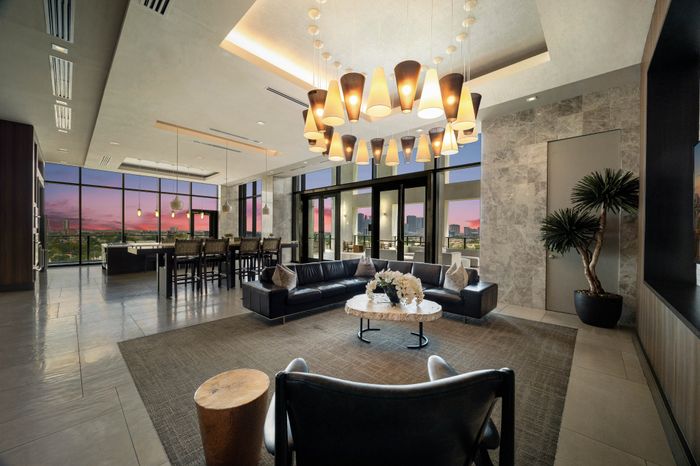 large club room with l-shaped sofa and bar height dining table under a large circular light fixture