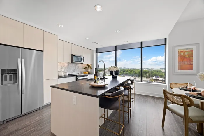 kitchen with large windows, center island with black stone counters, white wood cabinets, and stainless steel appliances