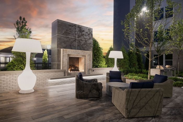 outdoor fireplace with stone backing and 4-chair seating area and 2 white decorative lamps