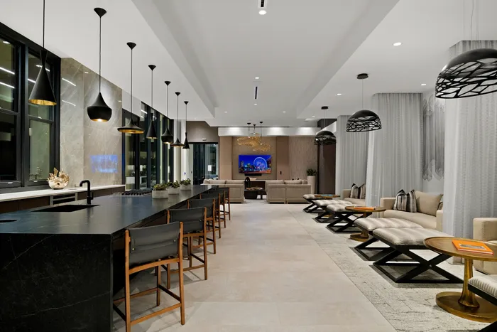 club room area with catering kitchen and counter seating and 3 lounge seating arrangements, partially separated by curtains