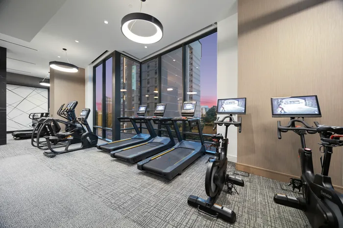 apartment gym with treadmills, stationary bikes, and additional cardio machines facing wall with floor to ceiling windows