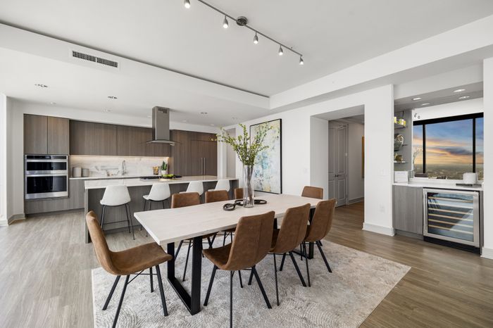 kitchen with dry bar, wine fridgem large dining table with 8 chairs and kitchen with island in the background