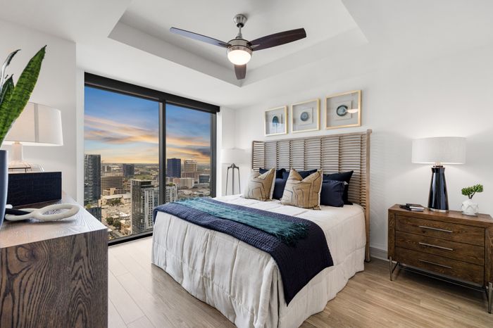bedroom with king size bed, a night stand and a dresser with floor to ceiling window