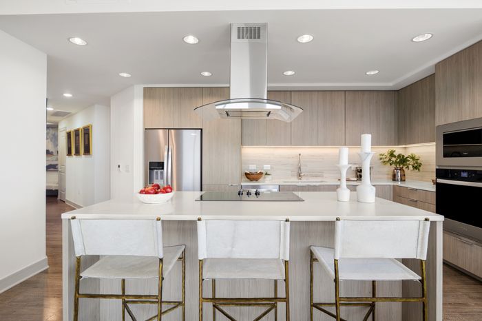 kitchen with island, thre bar stools and appliances like fridge, oven and stove in the background with cabinets