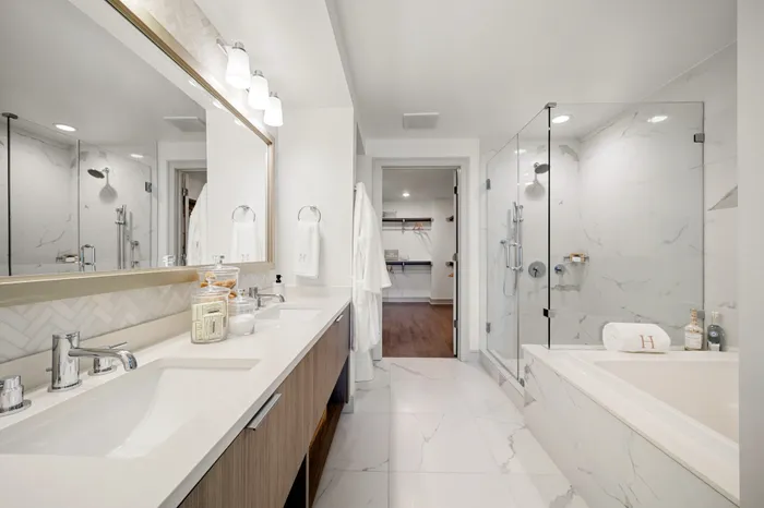 bathroom with standing glass shower, soaking tub, and a double vanity with closet in the back