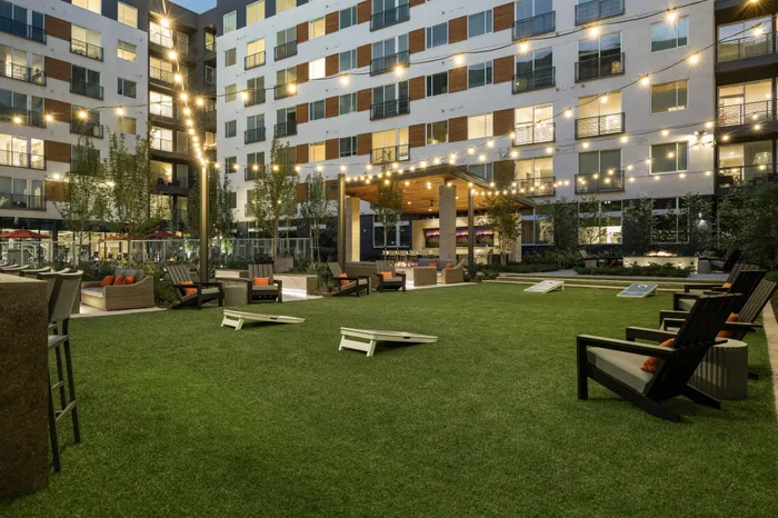 greenspace in apartment courtyard with lawn games, adirondack chairs, and string lighting