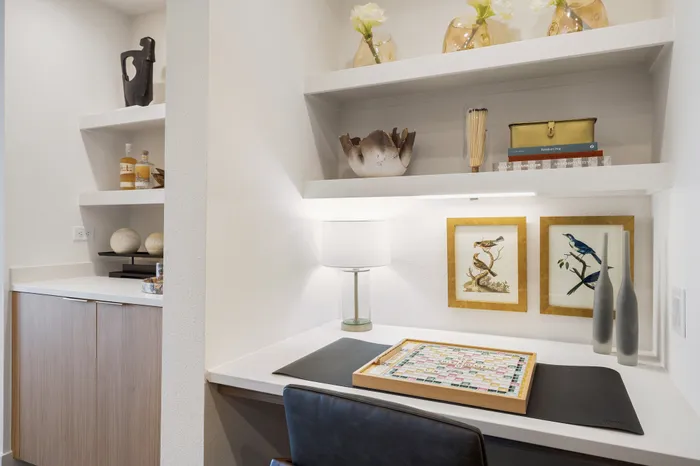 built-in desk with stone desk top and two shelves, next to dry bar with shelves and lower cabinets