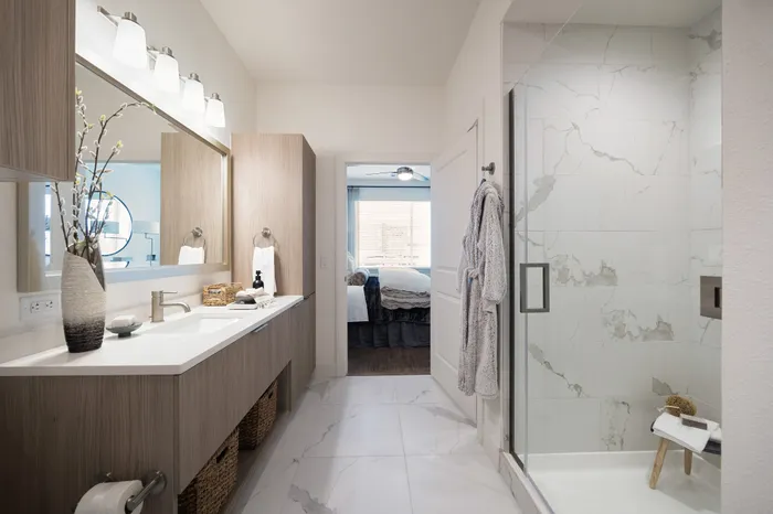 apartment bathroom with glass frameless shower, vanity with one sink and framed mirror