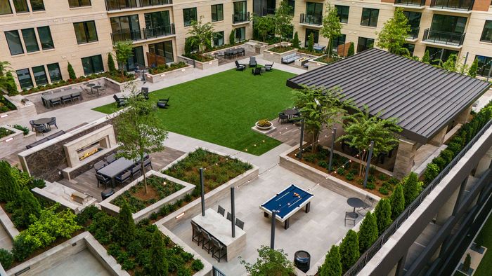 Courtyard amenities featuring arbor structure with seating, fireplaces, outdoor dining, pool table and open turf